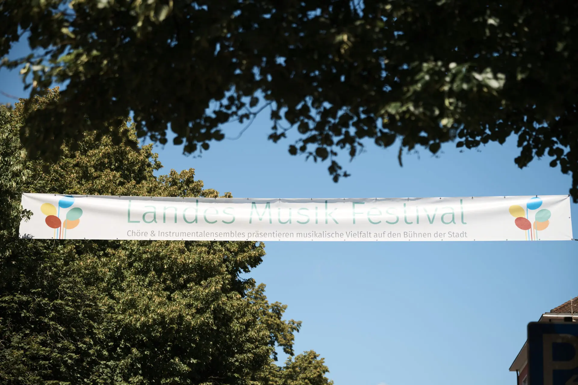 Bild von Banner des Landes-Musik-Festivals vor blauem Himmel und Bäumen